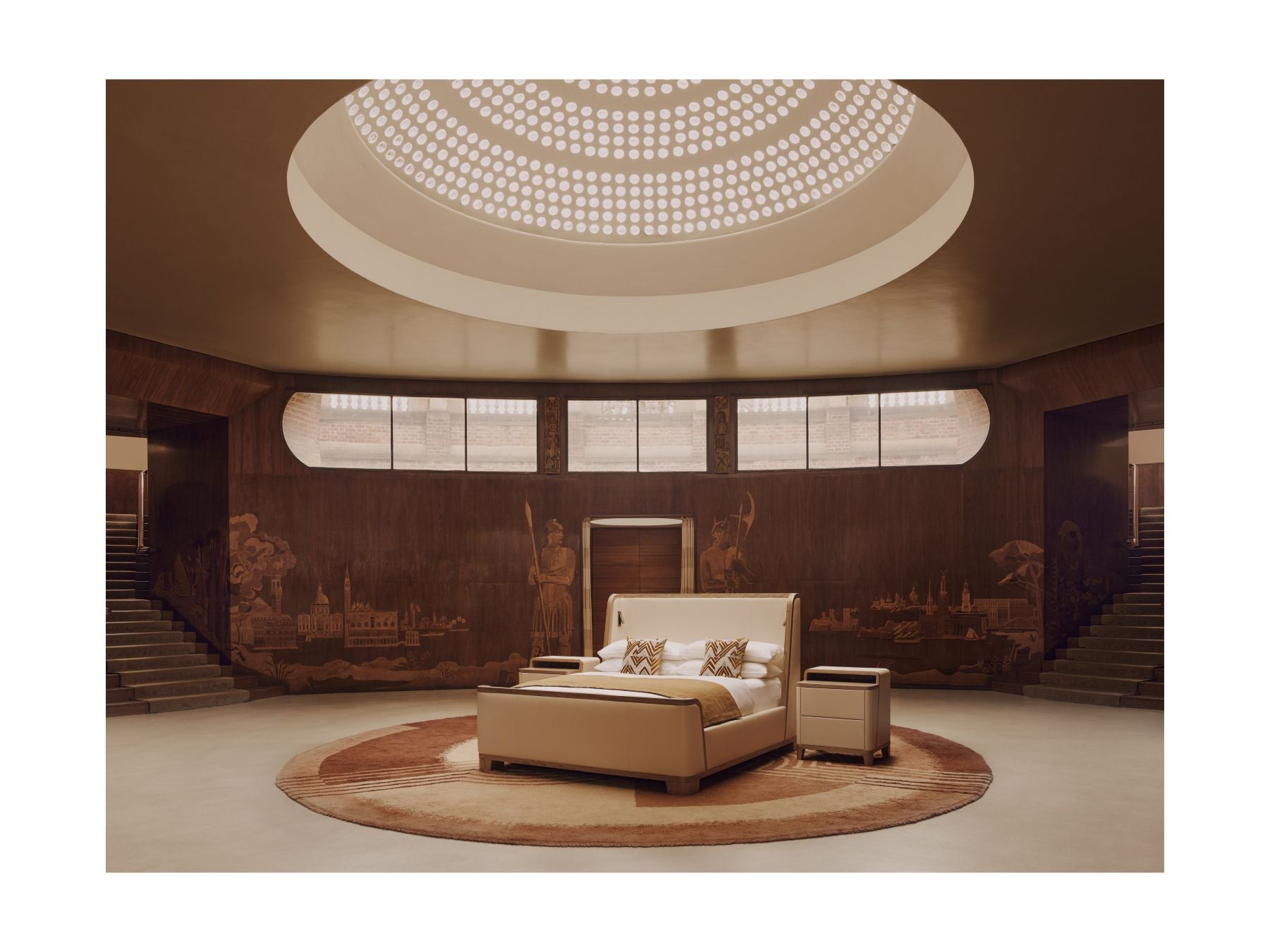 The Savoir Tranquility bed with a beige headbord set in a luxury bedroom with a large bed and round ceiling light fixture.