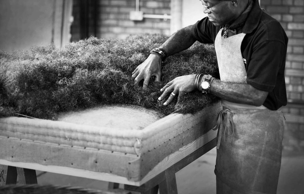 Black and white picture of a Savoir craftsman adding horse hair on a base