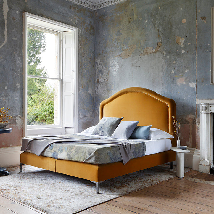 The Cassie bed with the mustard headboard and base completely dressed and set in a room
