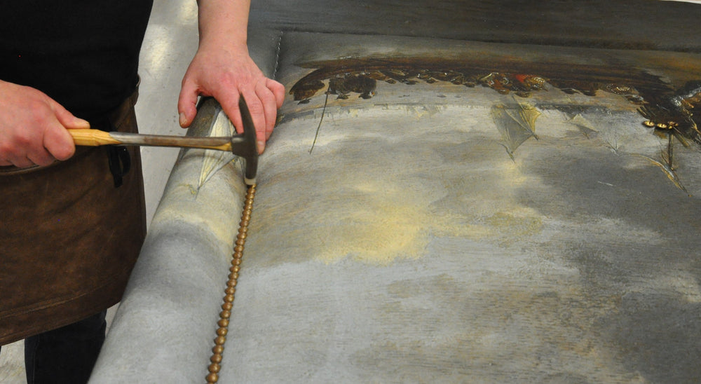 Old gold speckle nailing is applied by a Savoir craftsman to the Felix headboard.