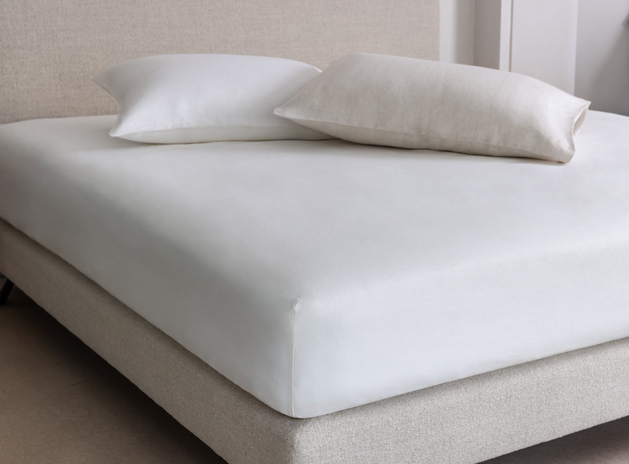 White fitted sheet on a Savoir bed with two pillows in a neutral room.