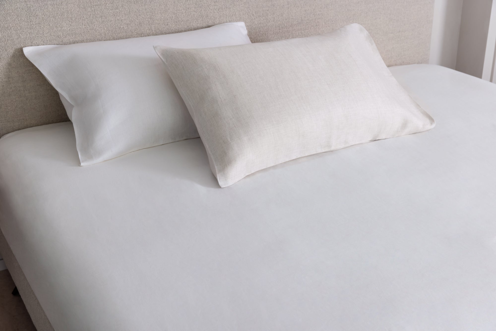 Two pillows on a bed with a tencel & linen fitted sheet and neutral Ian boucle headboard