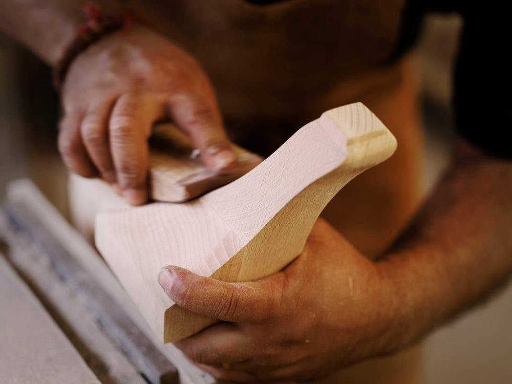 A close-up of a wooden bed leg being made