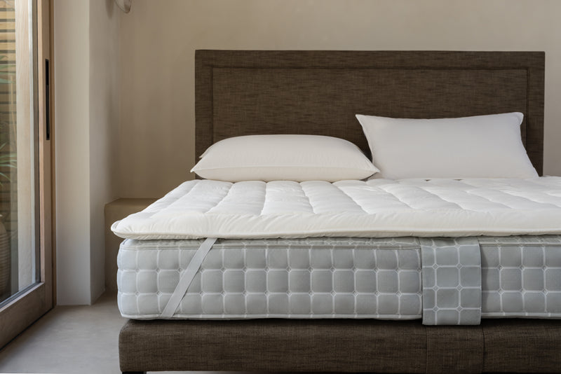 Luxury mattress protector secured to a Savoir mattress with elastic strap