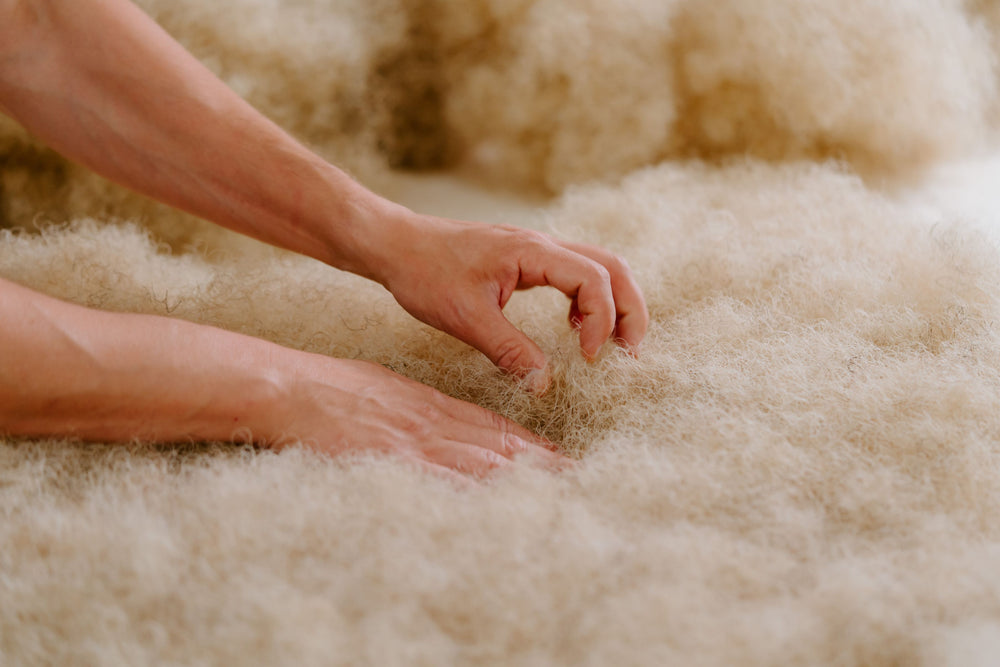 Close-up of a Savoir craftsman's hands positioning the soft, fluffy white horse hair.